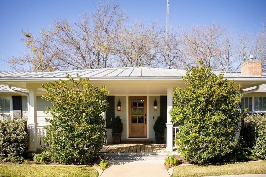 A charming single-story house with a wooden front door and a covered porch in McLennan County, Texas.