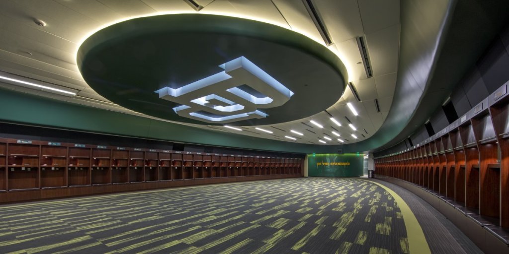 A modern, curved locker room with a large illuminated logo on the ceiling in McLennan County, Texas.