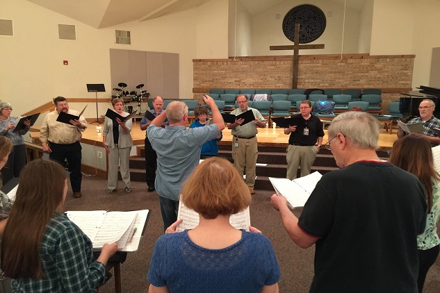 A choir practices in a church with a conductor leading them in McLennan County, Texas.