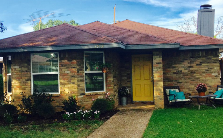 A single-story brick house with a yellow front door and a red roof in McLennan County, Texas.