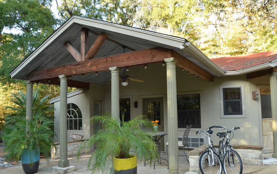 A covered patio with columns, potted plants, and two bicycles parked outside a house in McLennan County, Texas.