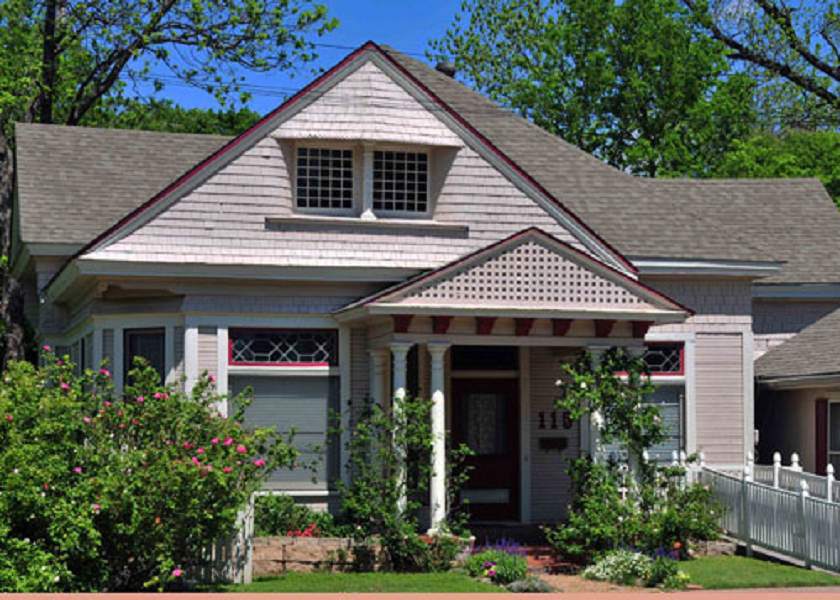 A charming light-colored house with a front porch and a small garden in McLennan County, Texas.