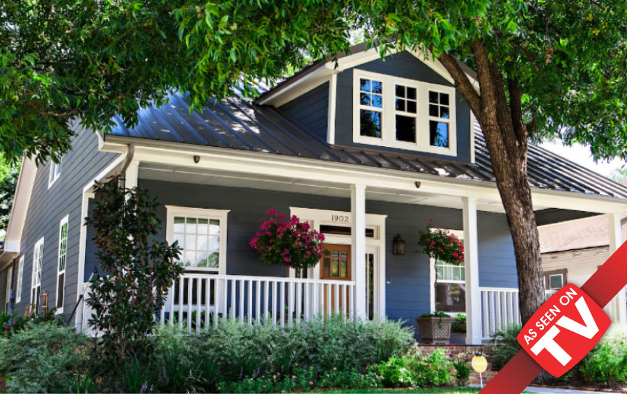 A charming blue house with a white porch and metal roof surrounded by trees in McLennan County, Texas.
