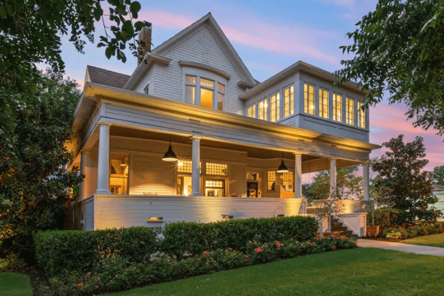 A beautiful white historic home with a large porch at sunset in McLennan County, Texas.