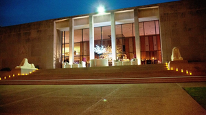 A modern building entrance with illuminated steps and statues at night in McLennan County, Texas.