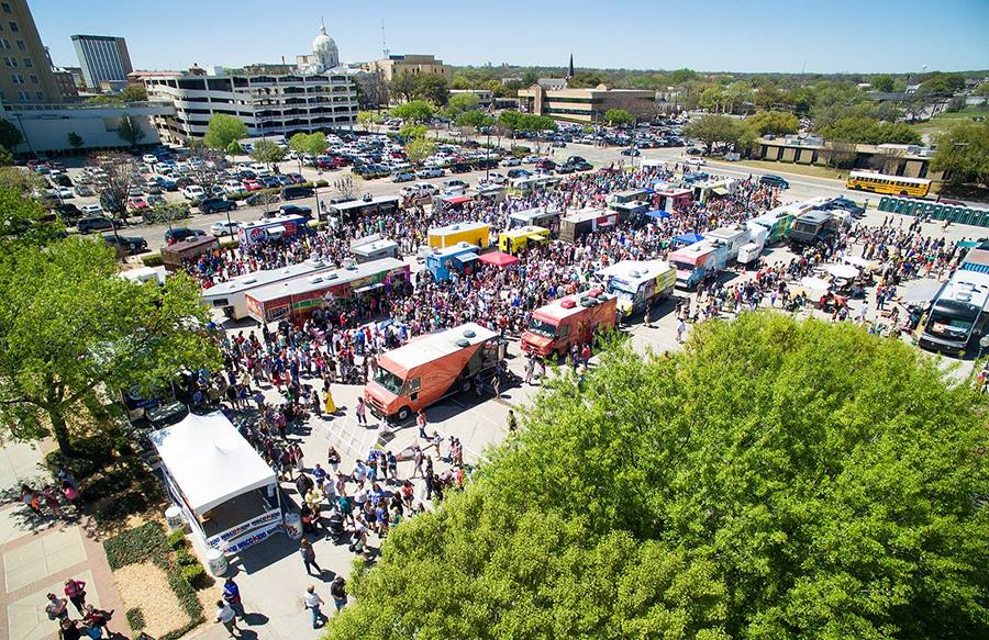A high-angle view of a crowded outdoor food truck festival in a parking lot in McLennan County, Texas.