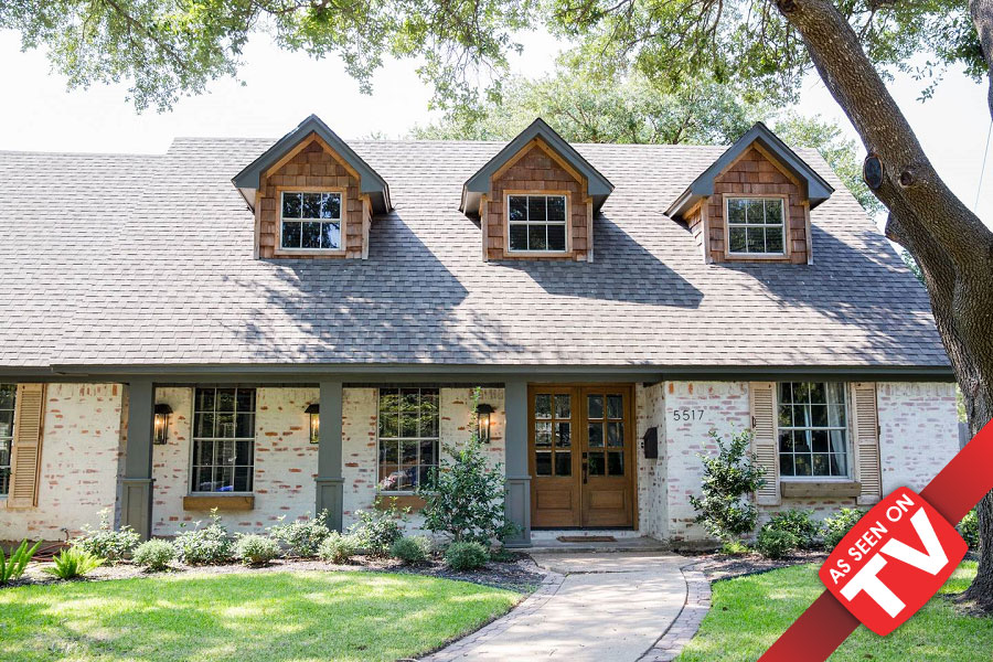 A charming two-story brick house with dormer windows and a wooden front door in McLennan County, Texas.