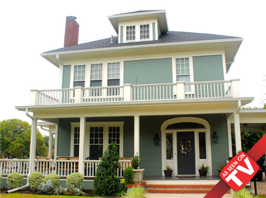 A two-story sage green house with a large front porch and a balcony in McLennan County, Texas.