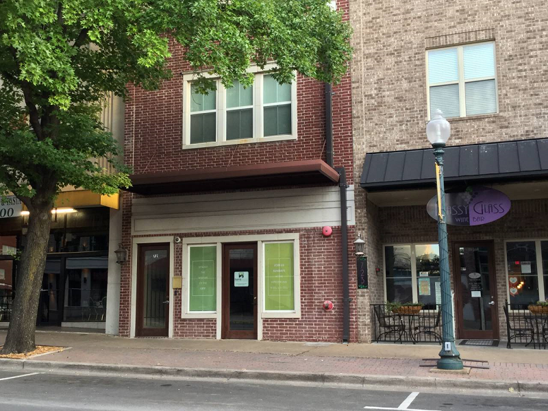 A brick building storefront with a wine bar next door on a city street in McLennan County, Texas.