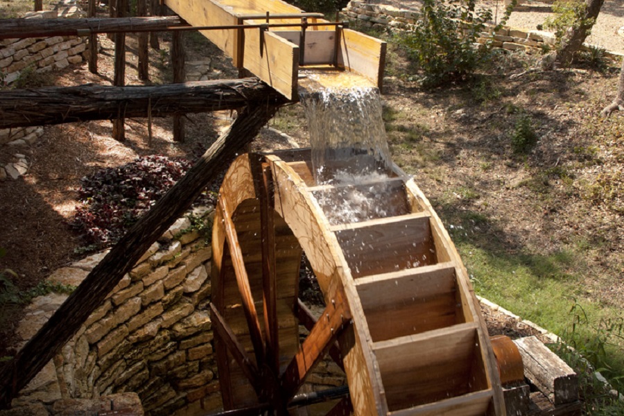 A wooden water wheel turning as water flows from a wooden flume in McLennan County, Texas.
