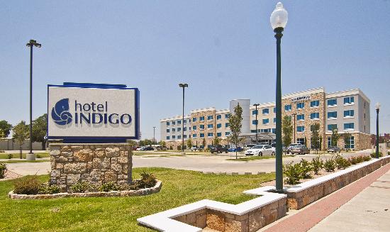 A Hotel Indigo sign stands in front of a modern hotel building in McLennan County, Texas.