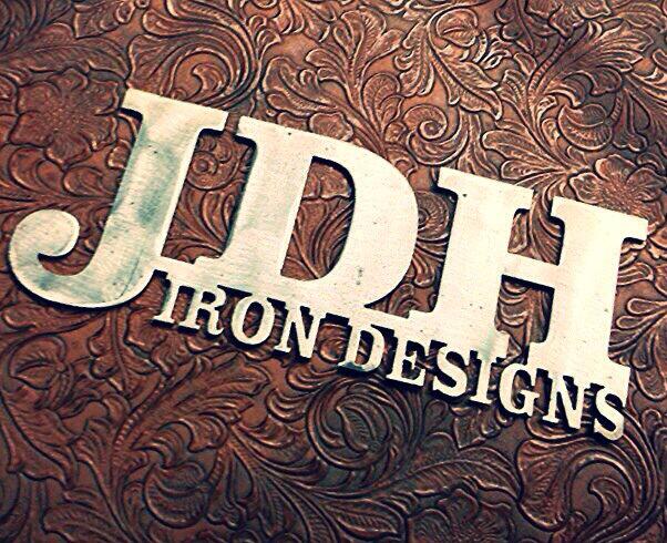 A metal sign reading JDH Iron Designs against a textured brown floral background in McLennan County, Texas.