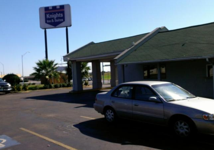 A silver sedan parked in front of a Knights Inn and Suites motel in McLennan County, Texas.