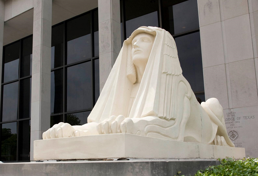 A white stone sphinx statue sits in front of a modern building in McLennan County, Texas.