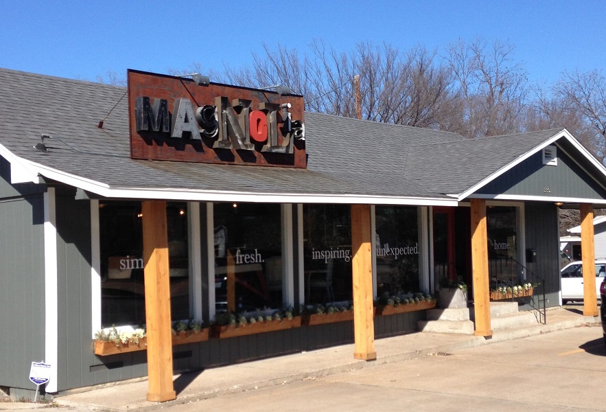 The exterior of a Magnolia store with a rustic metal sign and wooden pillars in McLennan County, Texas.