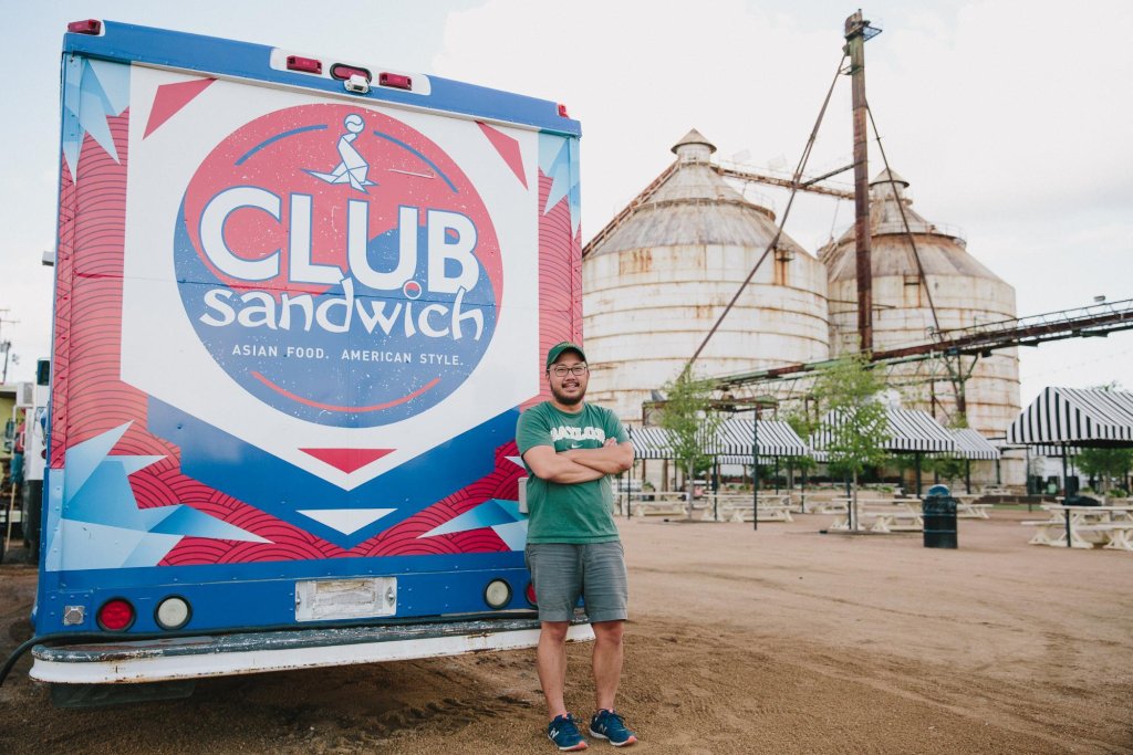 A man stands with arms crossed in front of a Club Sandwich food truck in McLennan County, Texas.