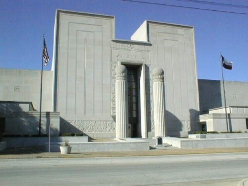 A large, stone Art Deco building with two prominent columns and flags flying outside in McLennan County, Texas.
