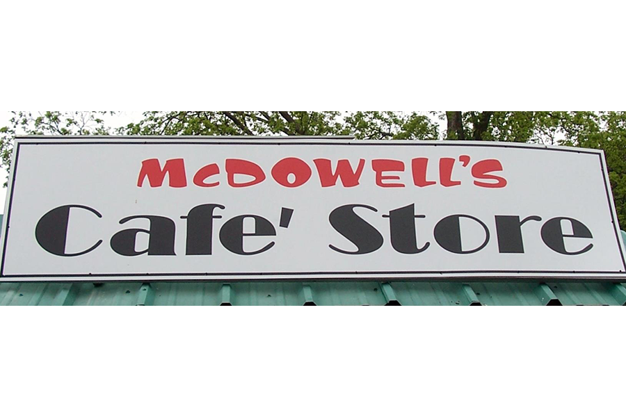 A rectangular sign for McDowell's Cafe' Store mounted above a green roof in McLennan County, Texas.