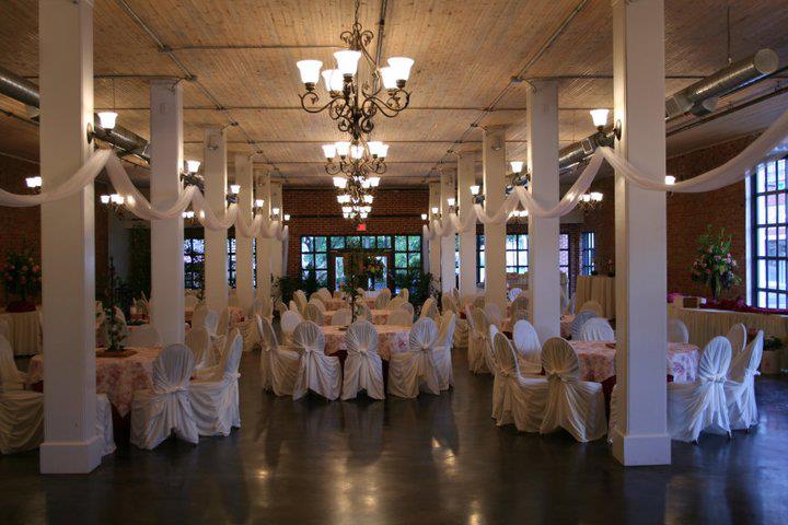 A spacious banquet hall decorated for a wedding with white chair covers and chandeliers in McLennan County, Texas.