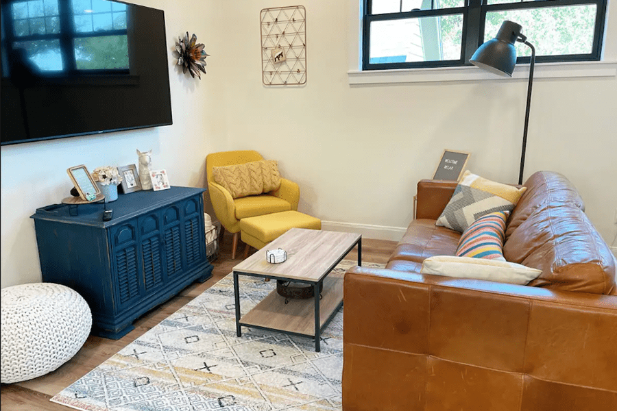A cozy living room featuring a brown leather sofa, yellow armchair, and blue cabinet in McLennan County, Texas.