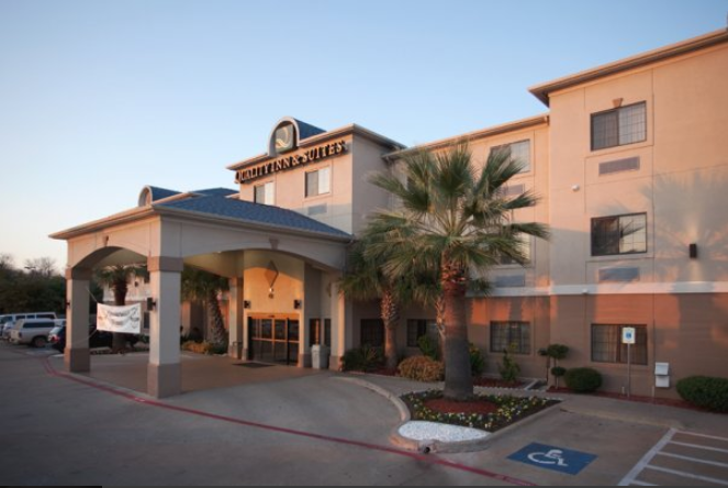 The exterior of a Quality Inn and Suites hotel at sunset in McLennan County, Texas.