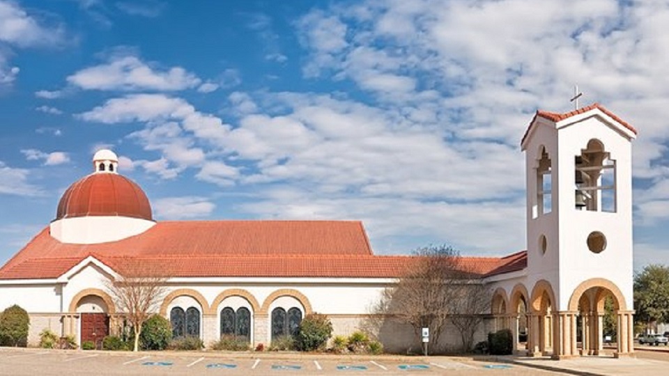 A white church building with a red dome and bell tower under a blue sky in McLennan County, Texas.