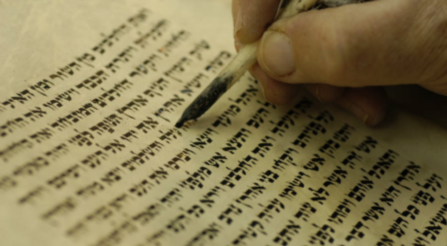 A hand uses a quill to write Hebrew text on parchment in McLennan County, Texas.