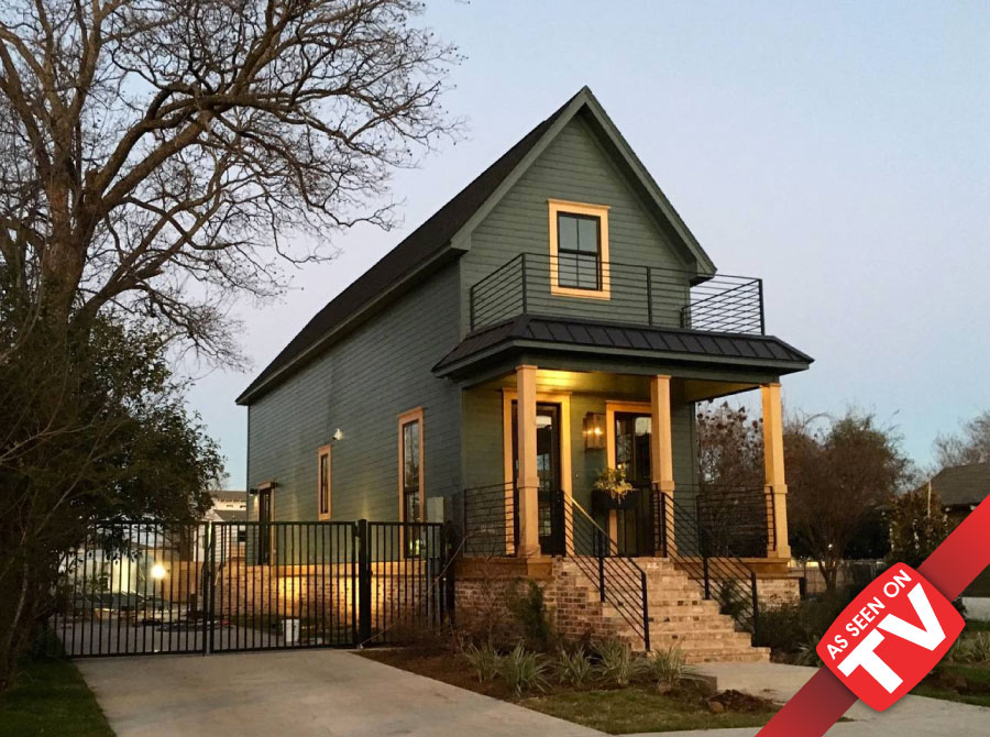 A green two-story house with a balcony and brick steps at dusk in McLennan County, Texas.