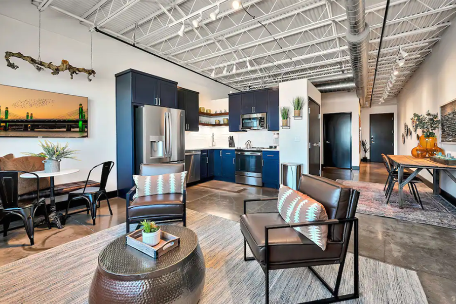 A modern open-concept apartment with dark blue kitchen cabinets and industrial-style decor in McLennan County, Texas.