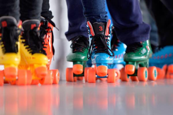 A group of people wearing colorful roller skates on a smooth indoor floor in McLennan County, Texas.