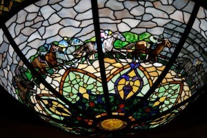A stained glass lamp shade featuring a horse race scene with jockeys in McLennan County, Texas.