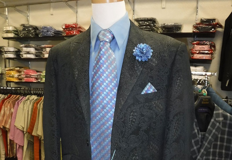 A mannequin wearing a black paisley suit, blue shirt, patterned tie, and blue lapel flower in McLennan County, Texas.