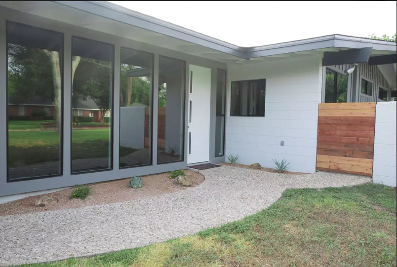 A modern mid-century home exterior with large windows, a white door, and gravel landscaping in McLennan County, Texas.
