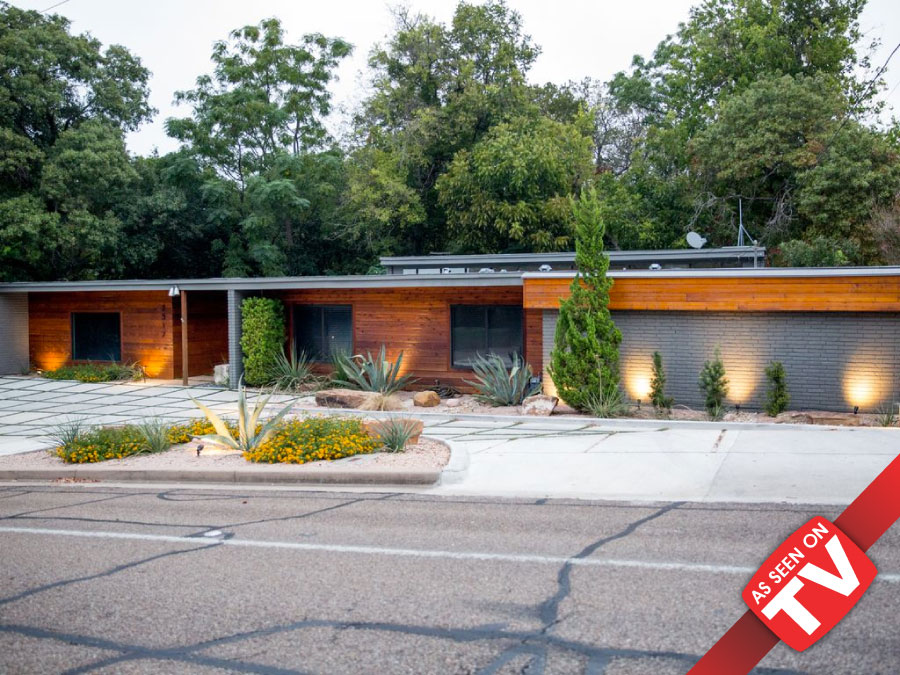 A modern mid-century style house with wood siding and stone accents at dusk in McLennan County, Texas.