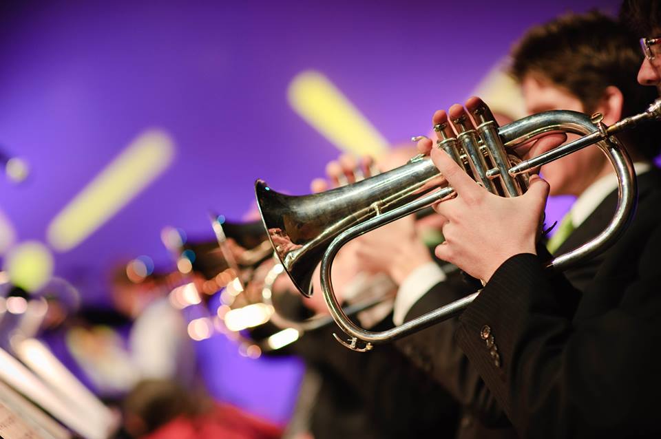 A musician playing a silver flugelhorn in an orchestra with a purple background in McLennan County, Texas.
