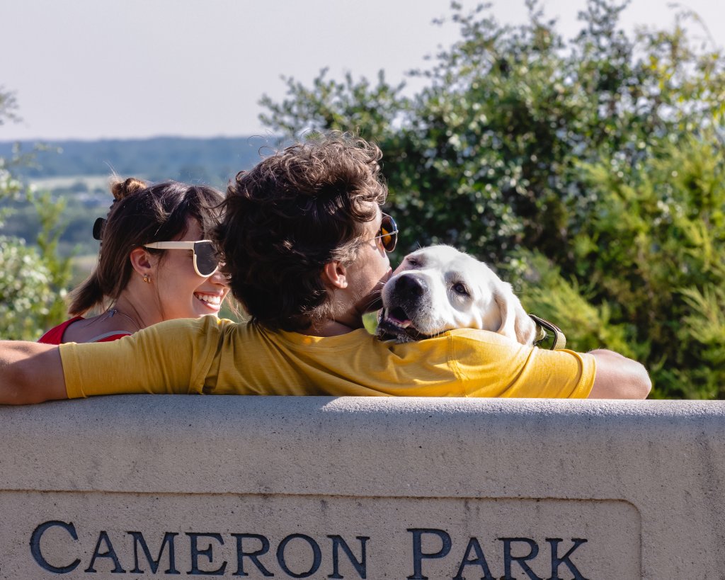 A couple sitting on a bench with their dog at Cameron Park in McLennan County, Texas.