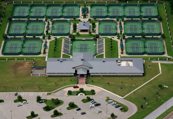 An aerial view of a large tennis complex with many courts and a clubhouse in McLennan County, Texas.