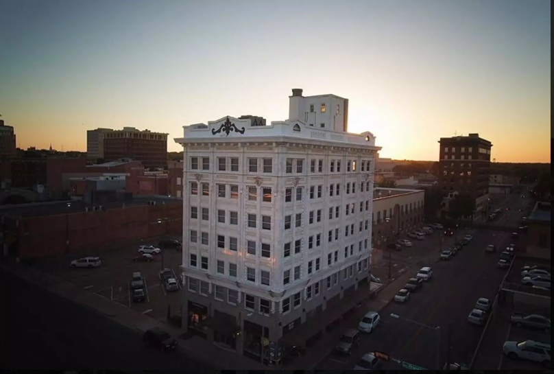 An aerial view of a historic white building during a golden sunset in McLennan County, Texas.
