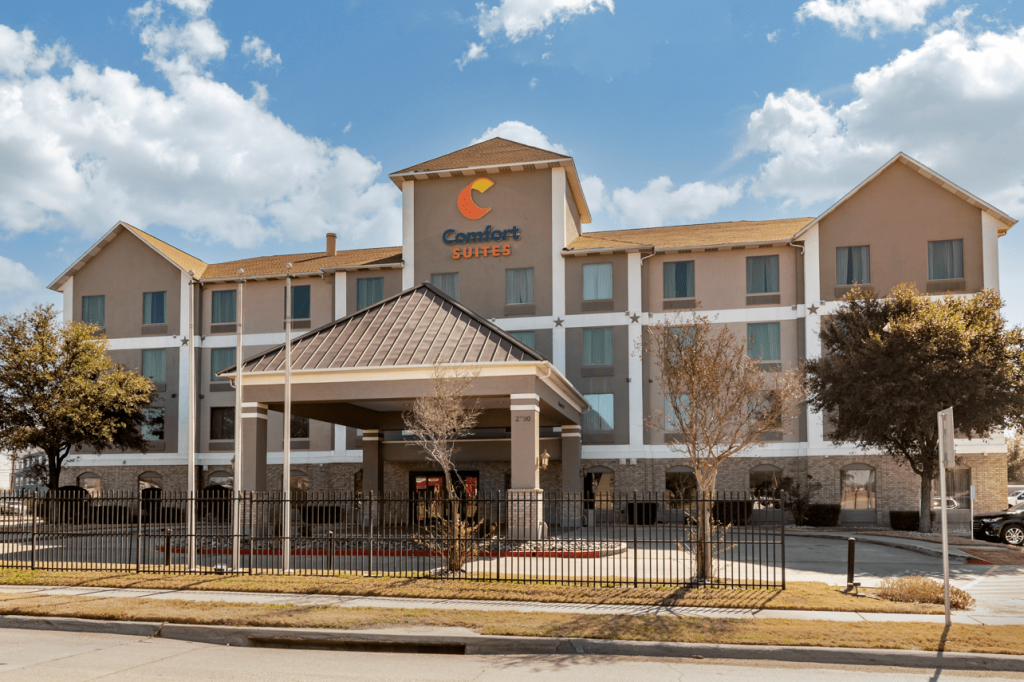 A Comfort Suites hotel building with a large entrance canopy and a metal fence in McLennan County, Texas.