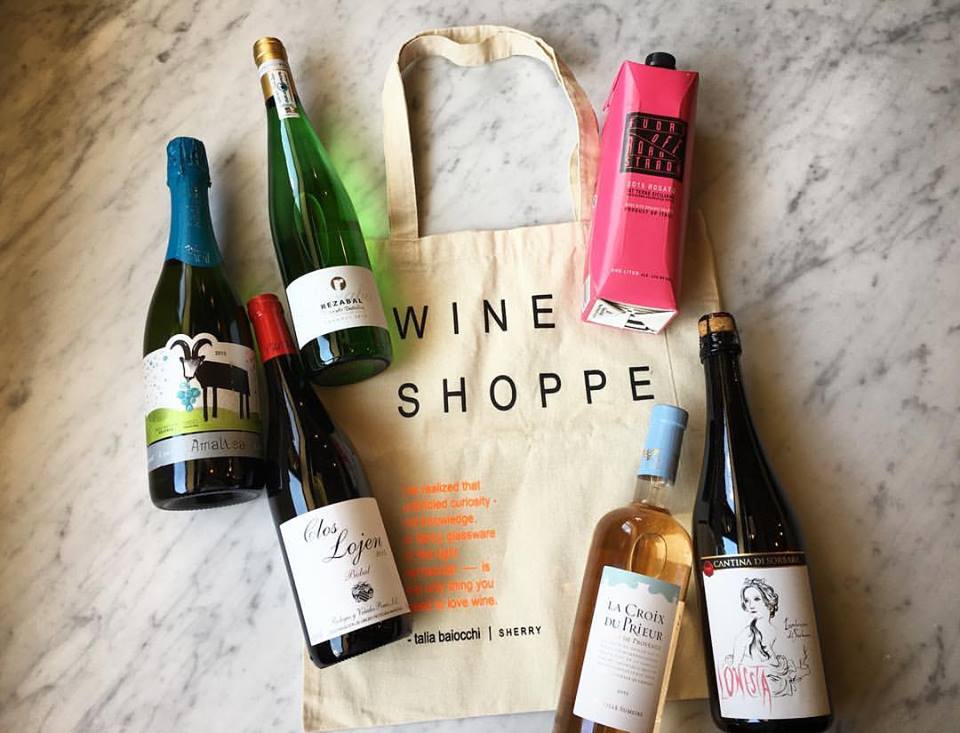 A canvas tote bag surrounded by several bottles of wine on a marble surface in McLennan County, Texas.