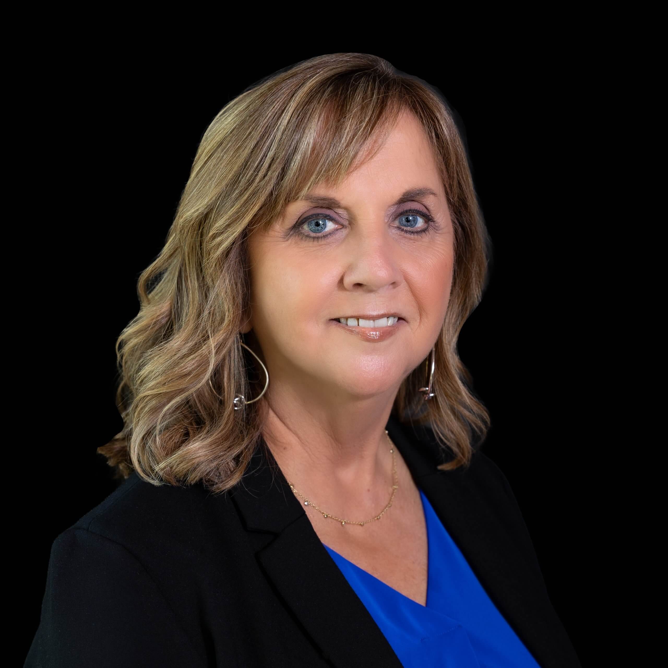 A middle-aged woman with blonde hair smiling against a black background in McLennan County, Texas.
