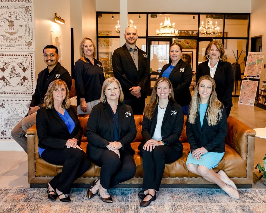 A group of nine professionals posing for a portrait in a modern office setting in McLennan County, Texas.