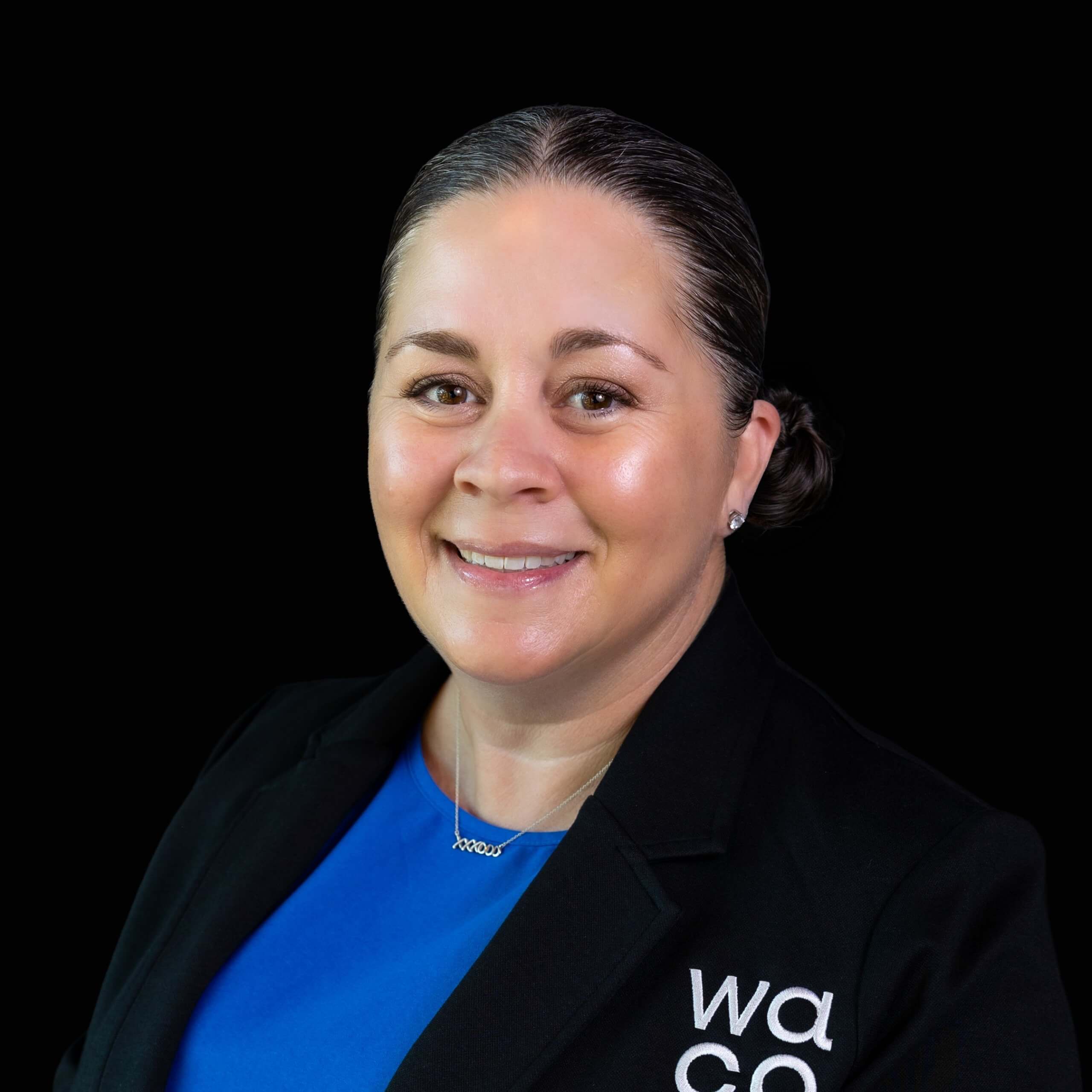 A smiling woman with dark hair pulled back wearing a blue shirt and black blazer in McLennan County, Texas.