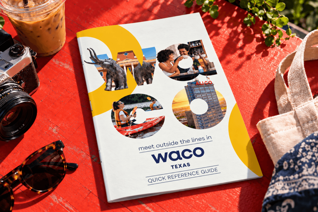 A Waco, Texas travel guide brochure resting on a bright red table with accessories in McLennan County, Texas.
