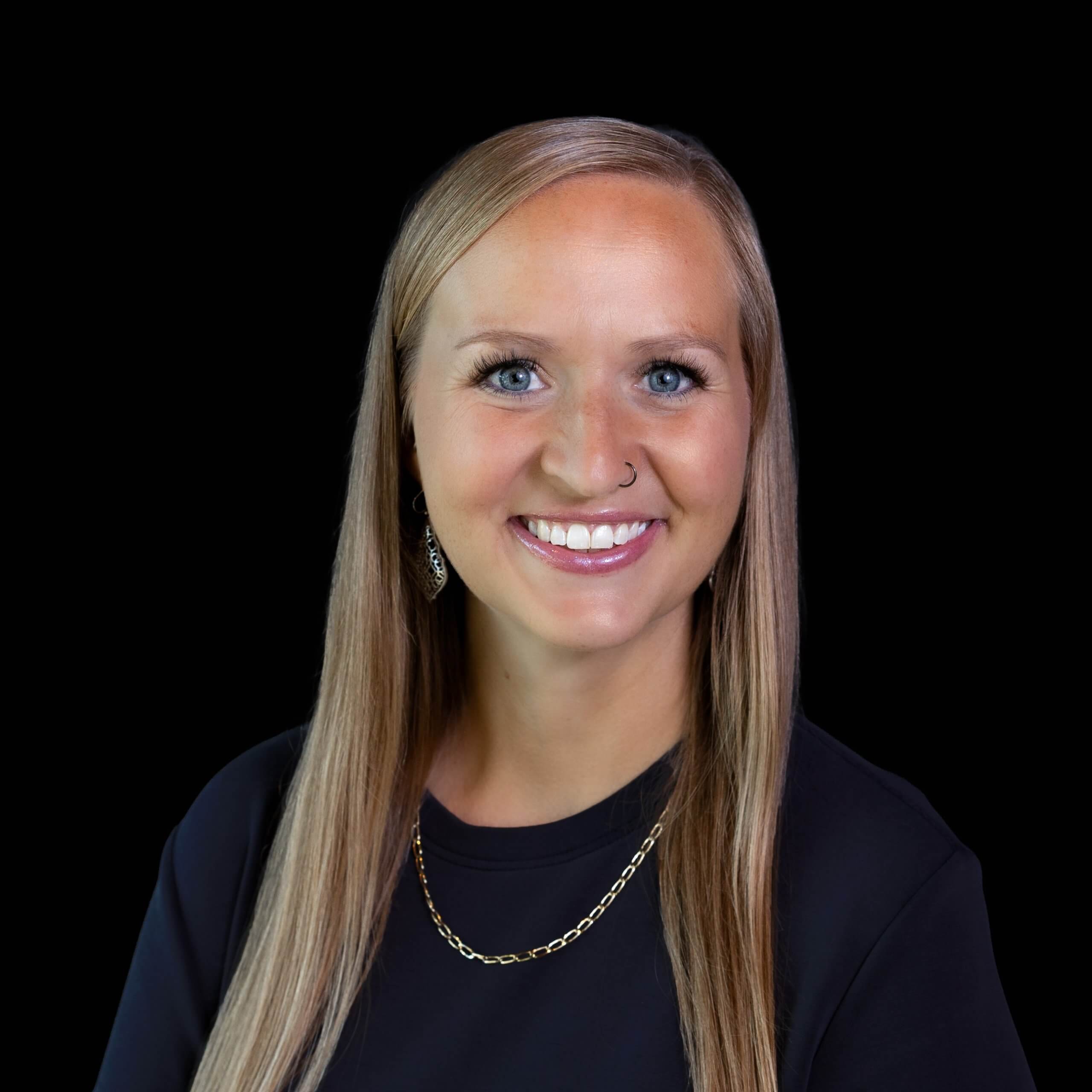 A smiling woman with long blonde hair against a black background in McLennan County, Texas.