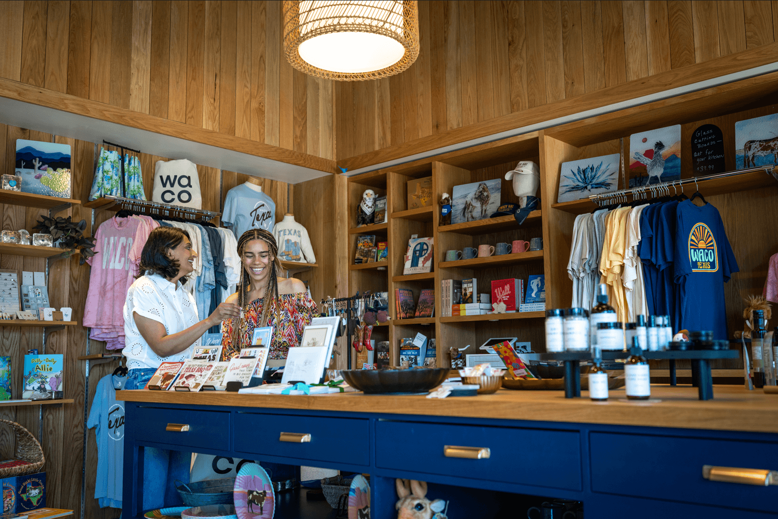 Two women smiling while shopping in a boutique store filled with Texas-themed merchandise in McLennan County, Texas.