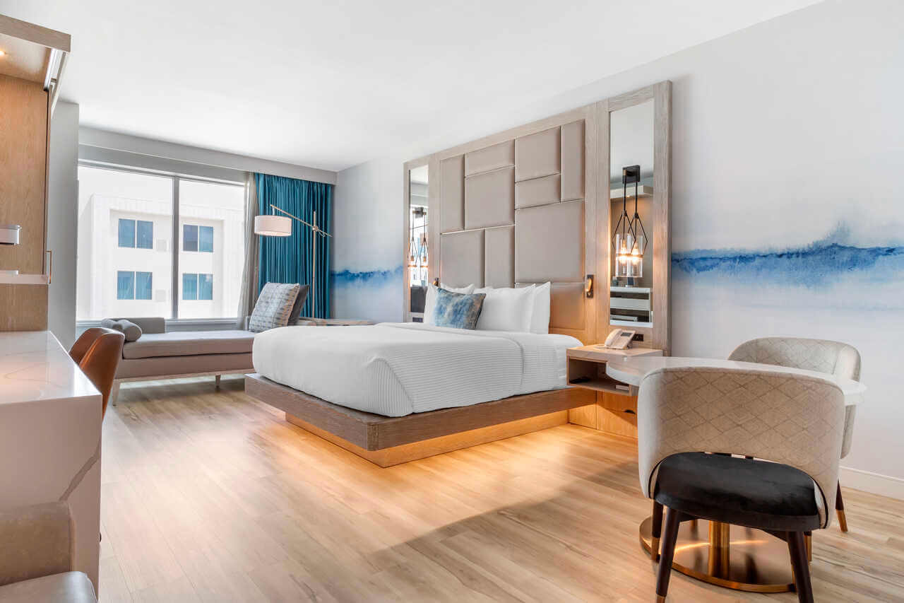 A modern hotel room with a queen bed, seating area, and blue wall art in McLennan County, Texas.