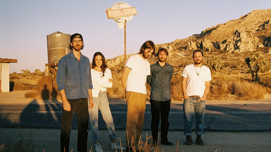 Five people standing in a desert landscape near a fuel stop sign in McLennan County, Texas.