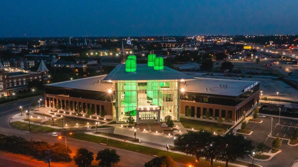 An aerial night view of a modern building with glowing green architectural towers in McLennan County, Texas.