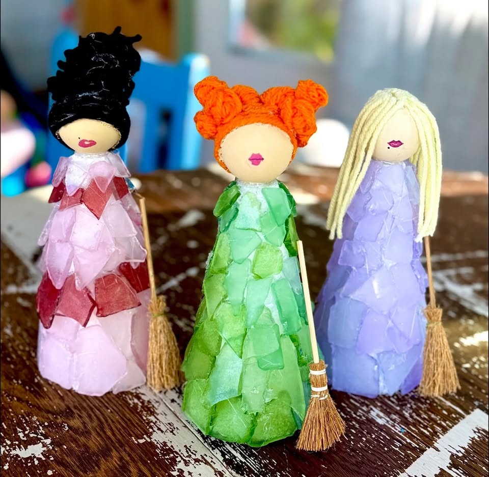 Three handmade witch dolls with sea glass dresses standing on a wooden table in McLennan County, Texas.